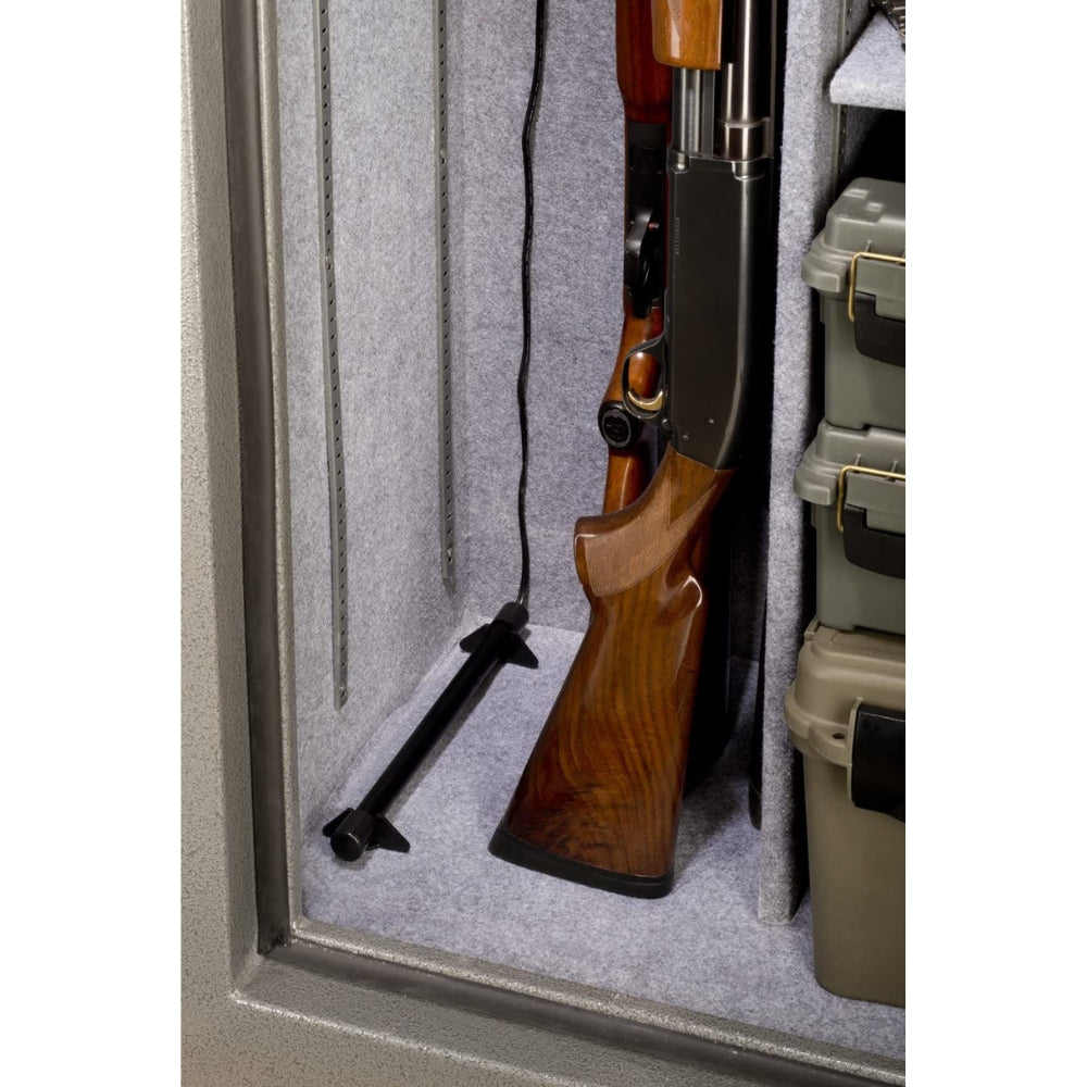 Close-up of a Stack-On SPAD-12 Electronic Safe Dehumidifier rod installed in a gun safe beside a wooden stock shotgun, with power cords visible along the safe’s grey felt-lined wall.