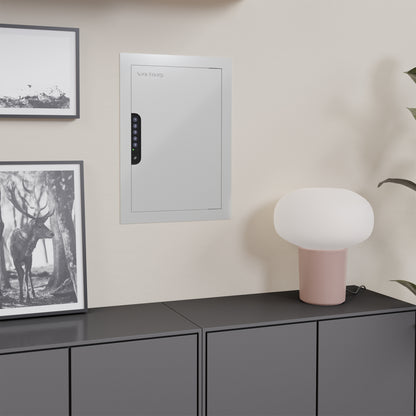 White in-wall safe installed behind a painting in a home office, showcasing its discreet and hidden design.